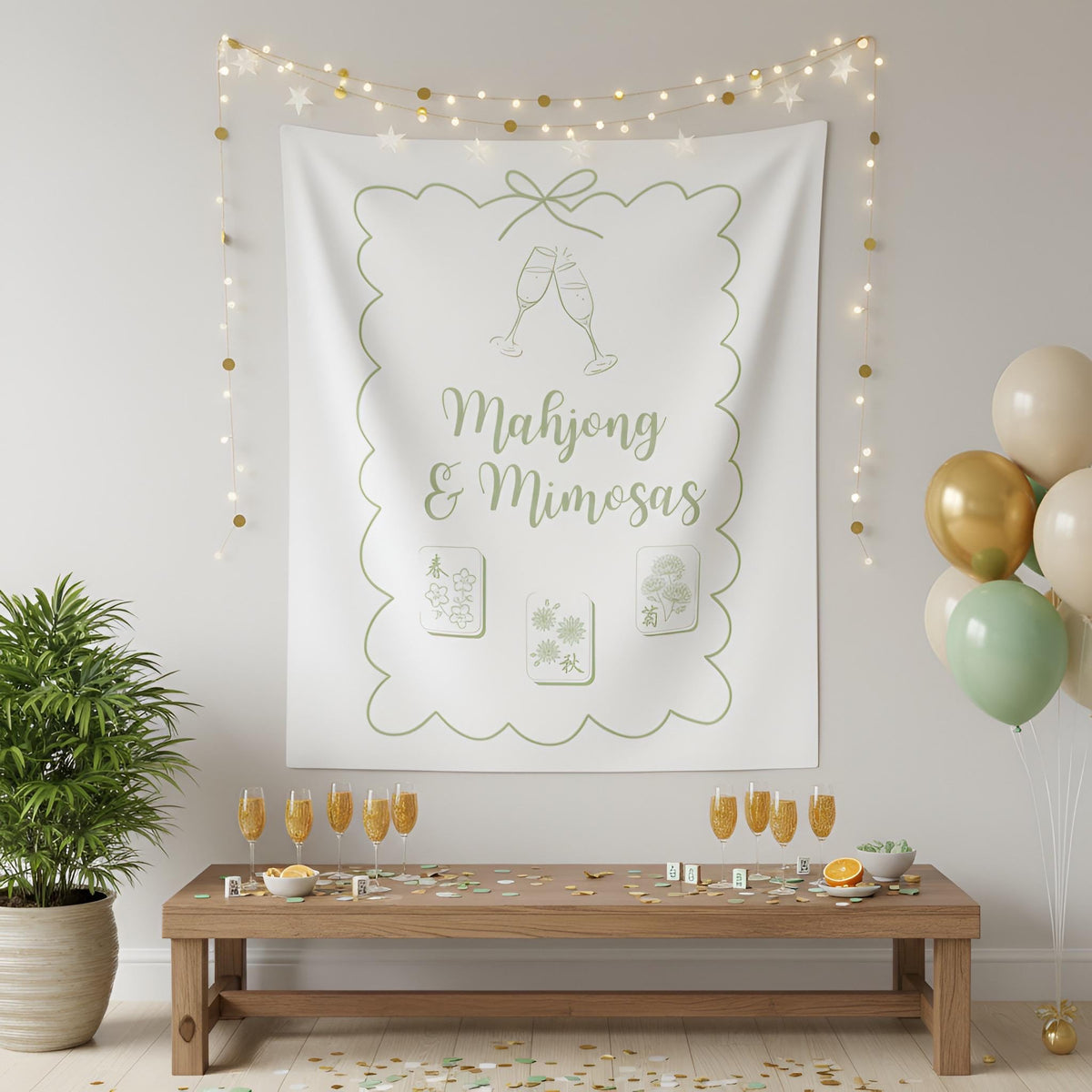 A white fabric wall tapestry with a scalloped border and champagne toast graphic, printed with the text 'Majong & Mimosas' in sage green. The tapestry is hanging on a light gray wall in a decorated room with string lights, a wooden table, and balloons.