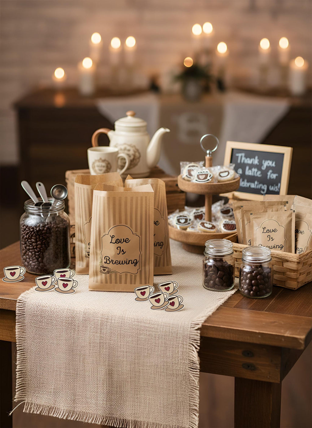 A rustic coffee-themed display on a wooden table with kraft paper bags reading 'Love Is Brewing,' small jars of coffee beans, teacups, a teapot, and a sign that says 'Thank you for drinking with us.' The scene is warmly lit by blurred candles in the background.