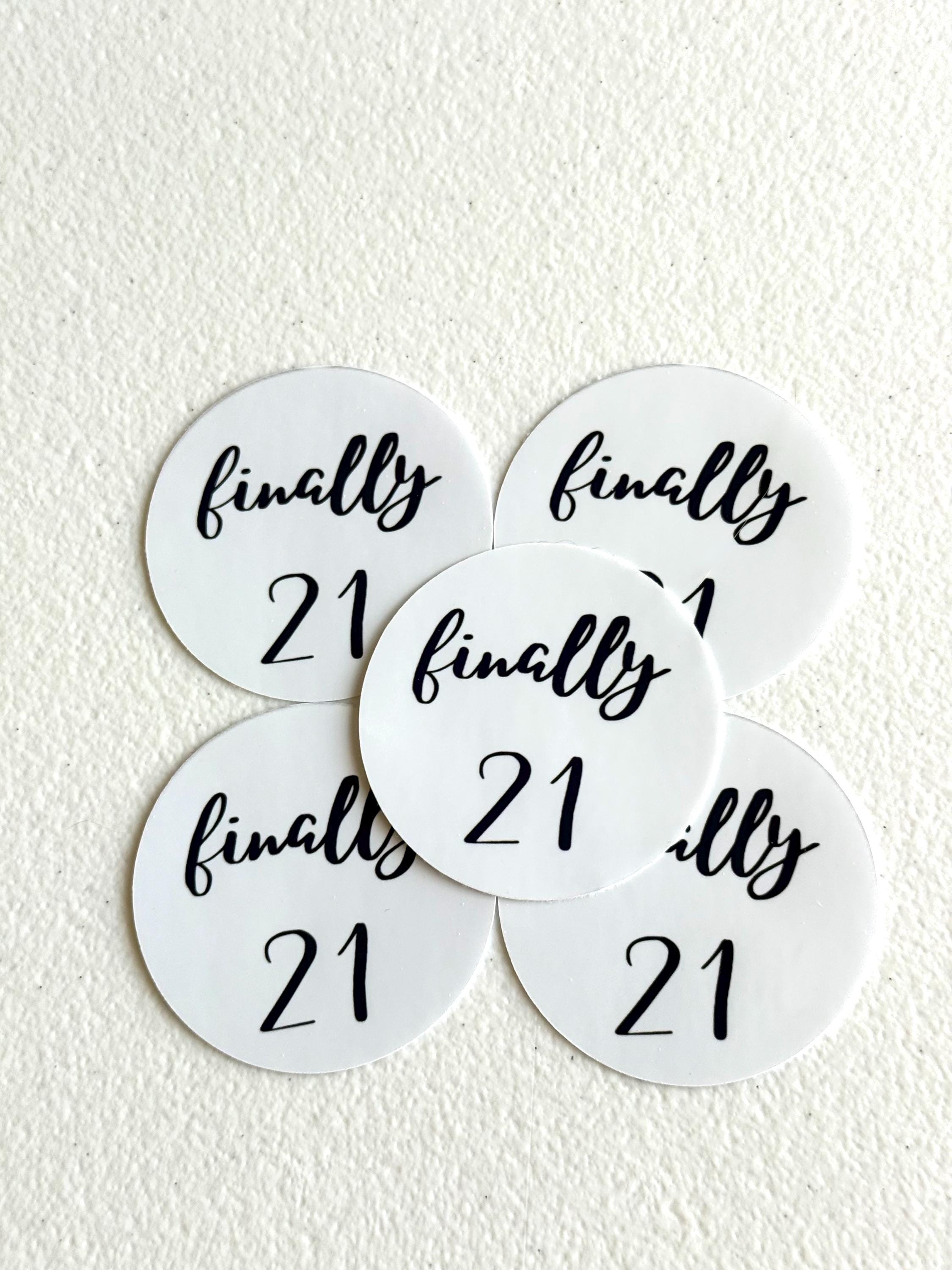 Five round white table place cards with black script reading 'finally 21' arranged on a textured off-white surface.