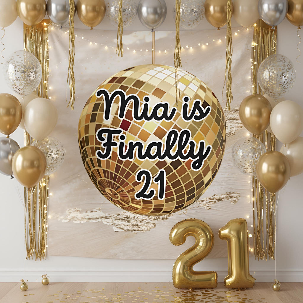 A gold disco ball balloon with the text 'Finally 21' in black script, displayed against a decorated party backdrop with gold and silver balloons, gold tinsel, string lights, and gold number 21 foil balloons on the floor.
