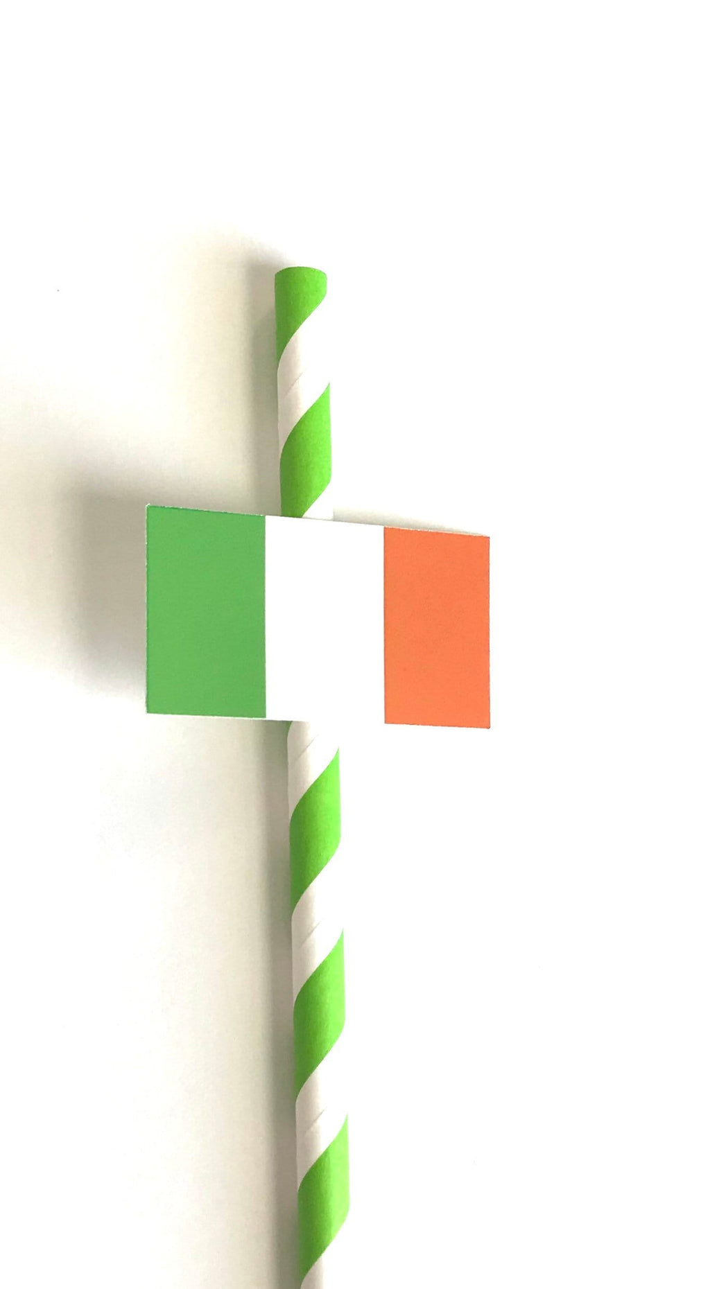 A paper straw with green and white diagonal stripes, crossed with a small paper flag featuring green, white, and orange vertical bands, on a plain white background.