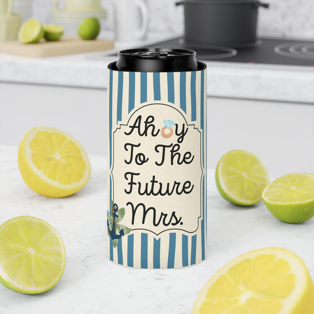 A slim can cooler sleeve with a black lid, featuring a blue and white striped pattern and the text 'Ahoy To The Future Mrs.' with a small anchor and floral design, set on a kitchen counter surrounded by lemons and limes.