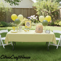 A yellow tablecloth-covered party table set up outdoors on a grassy lawn, decorated with yellow and green balloons, white folding chairs, paper bags, and a sign that reads 'zest wishes For The Mrs.' A CitrusCraftHouse watermark appears at the bottom left.