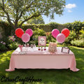 A pink bachelorette party table setup in a backyard garden, featuring a light pink tablecloth, pink and red balloons, party hats, cups, and signs including a 'Bachelorette for Life' sign. CitrusCraftHouse logo is visible in the bottom left corner. Berry in love