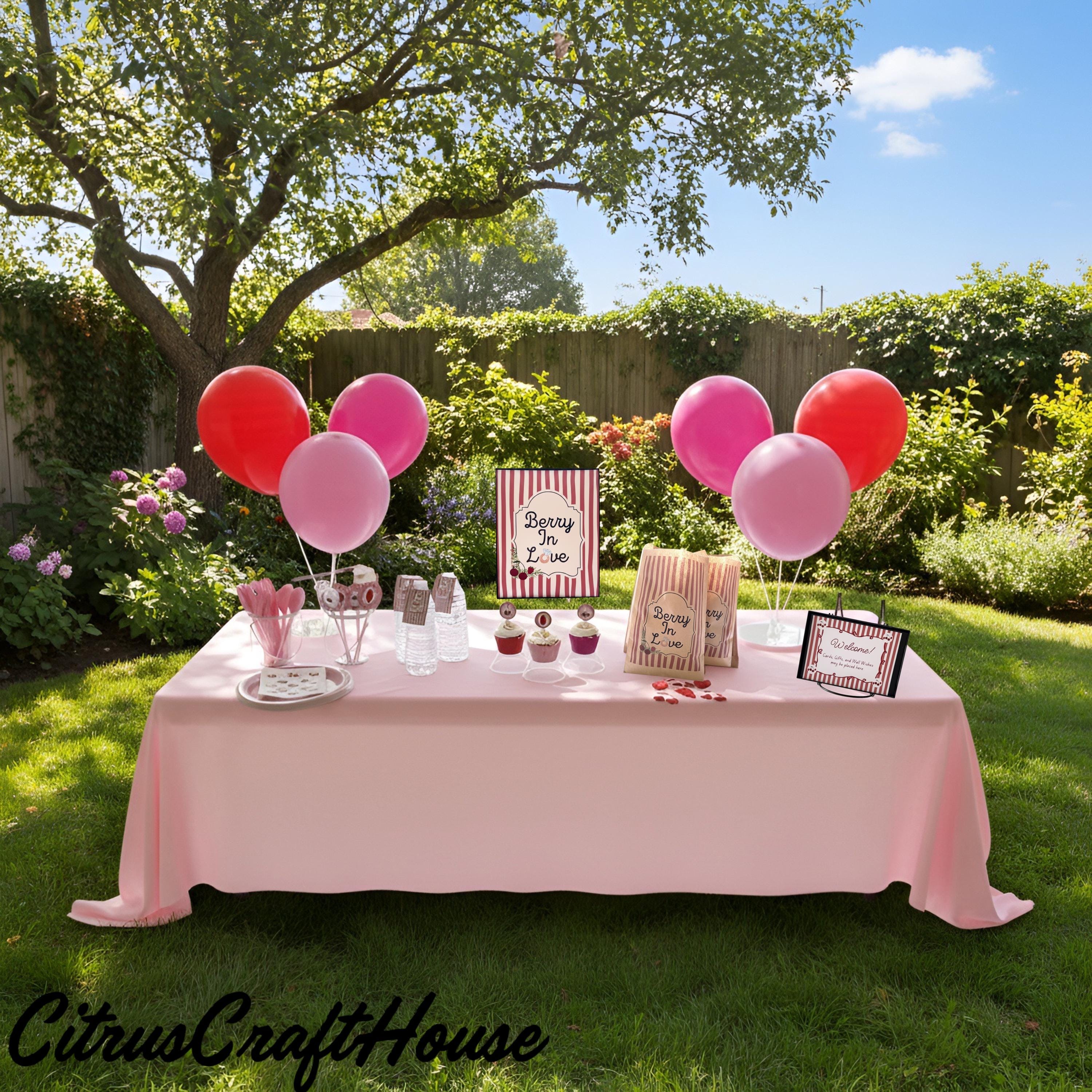 A pink bachelorette party table setup in a backyard garden, featuring a light pink tablecloth, pink and red balloons, party hats, cups, and signs including a 'Bachelorette for Life' sign. CitrusCraftHouse logo is visible in the bottom left corner. Berry in love