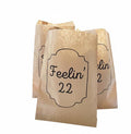 Three small kraft paper party favor bags with black printed text reading 'Feelin' 22' on a plain white background.