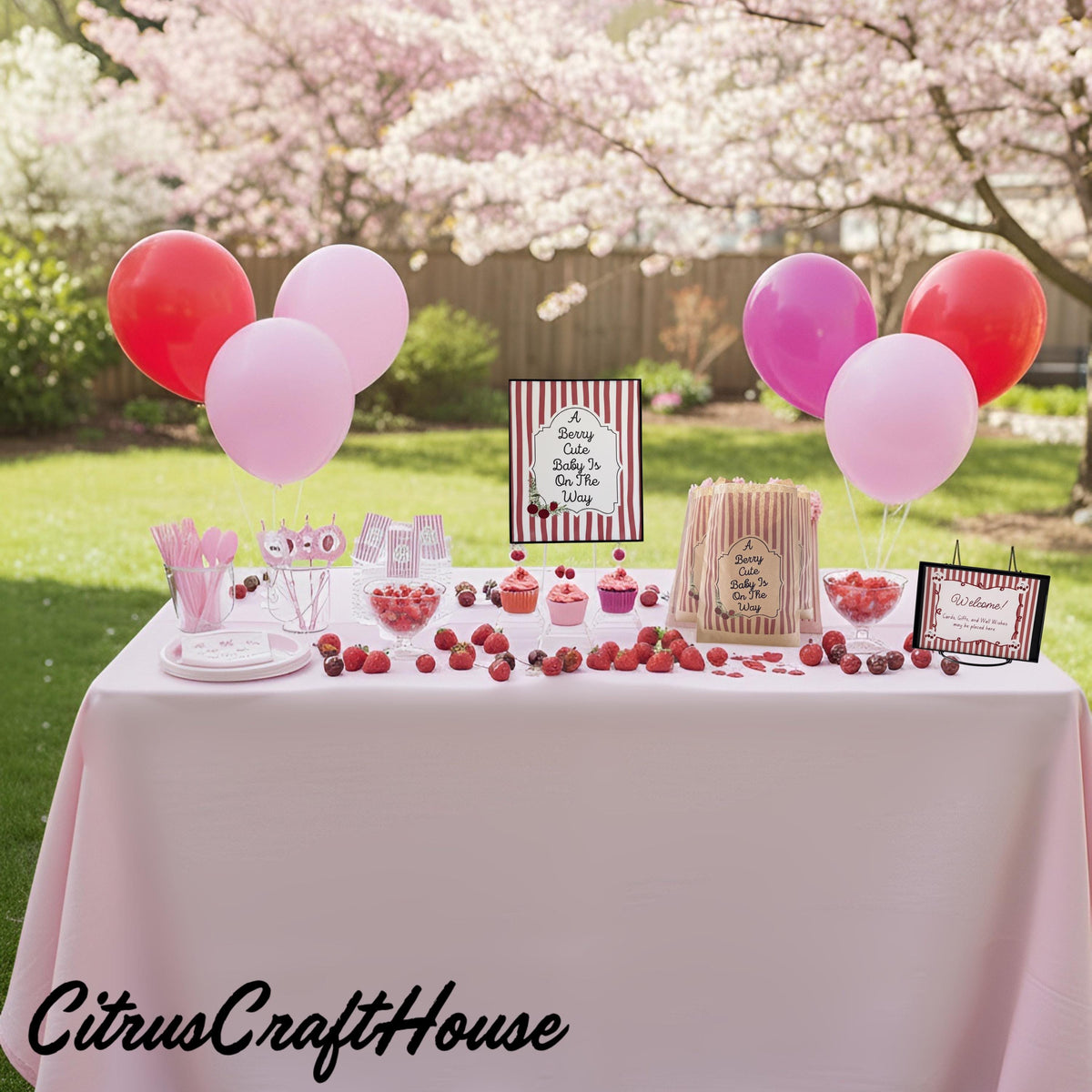 A pink-themed party dessert table outdoors with balloons, candy, and signs, with a CitrusCraftHouse watermark at the bottom left. A berry cute baby is on the way